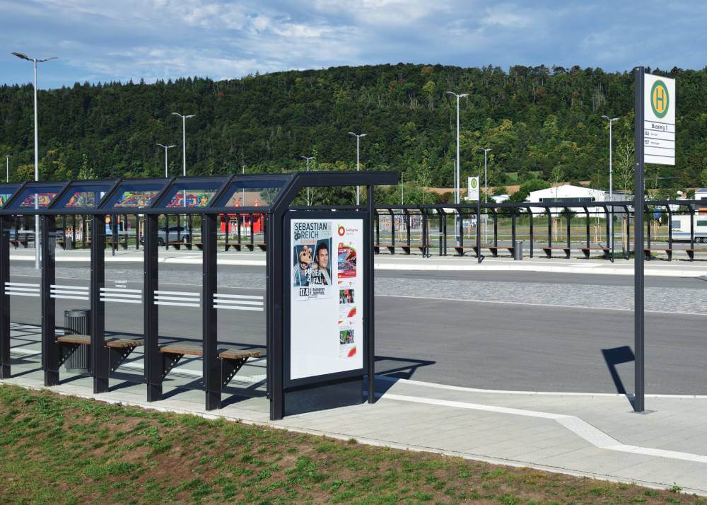 Schaukasten in einer modernen Wartehalle vor grüner Landschaft
