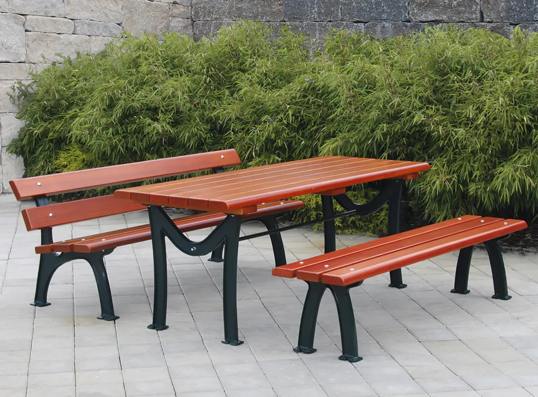 Bank-Tisch-Kombination ROMA mit rechteckigem Tisch, zwei Bänken und einer Bank mit Rückenlehne aus Holz und schwarzem Metallgestell auf gepflastertem Boden vor grünen Sträuchern.