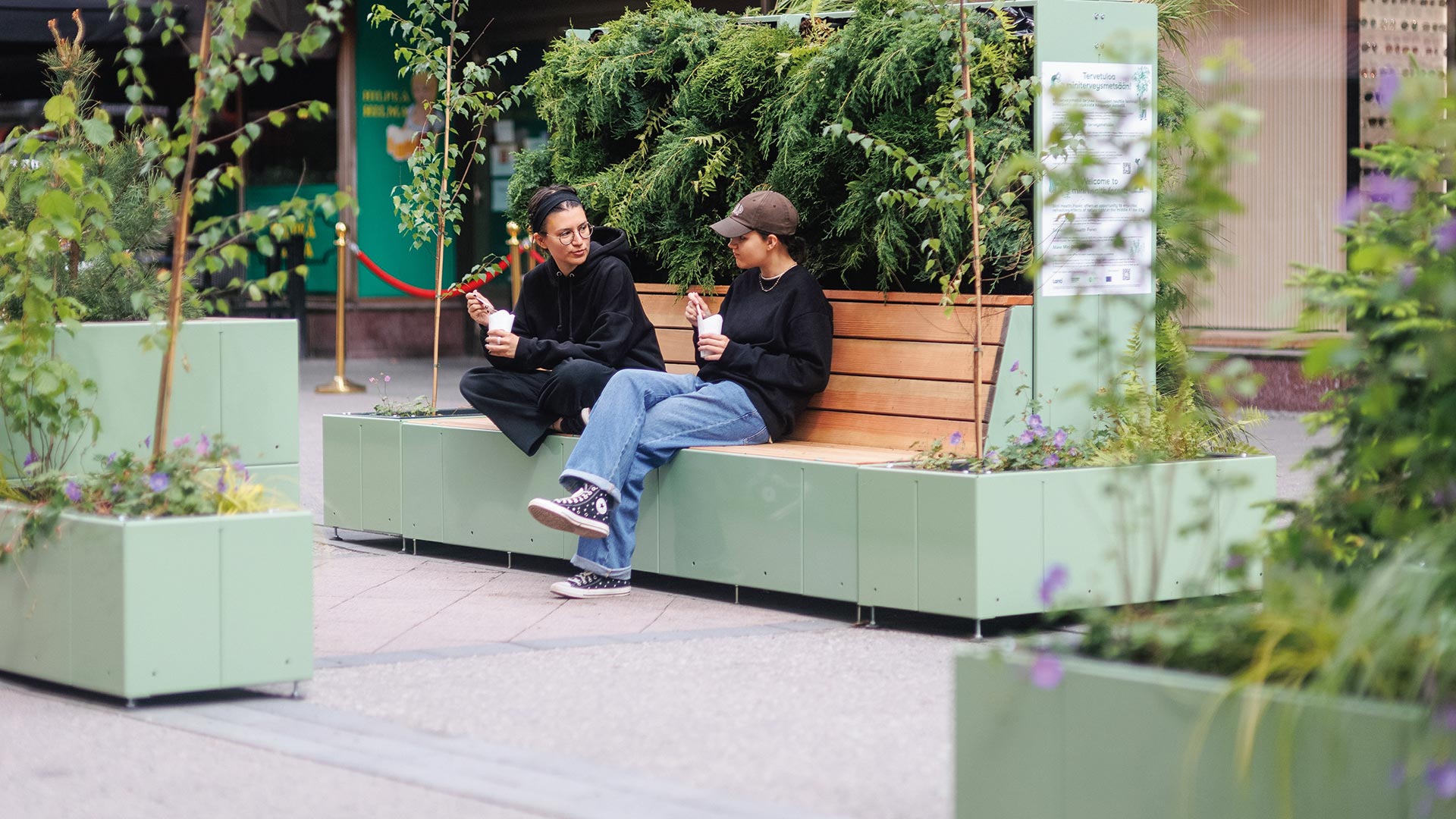 Begrünter Sitzinsel auf der zwei Frauen sitzen