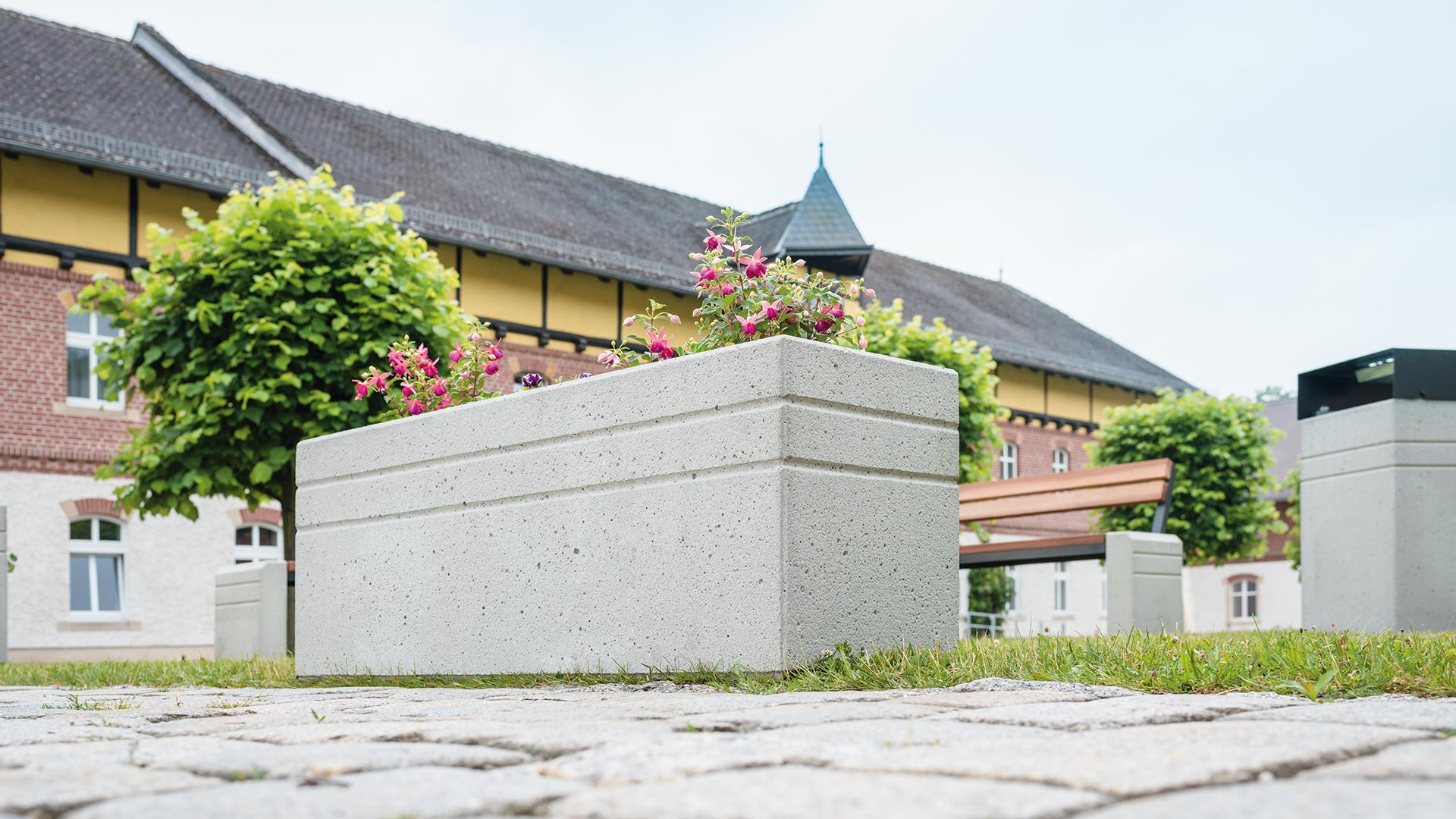 Moderne Pflanzbehälter aus Beton steht auf dem Vorhof eines Gehöfts