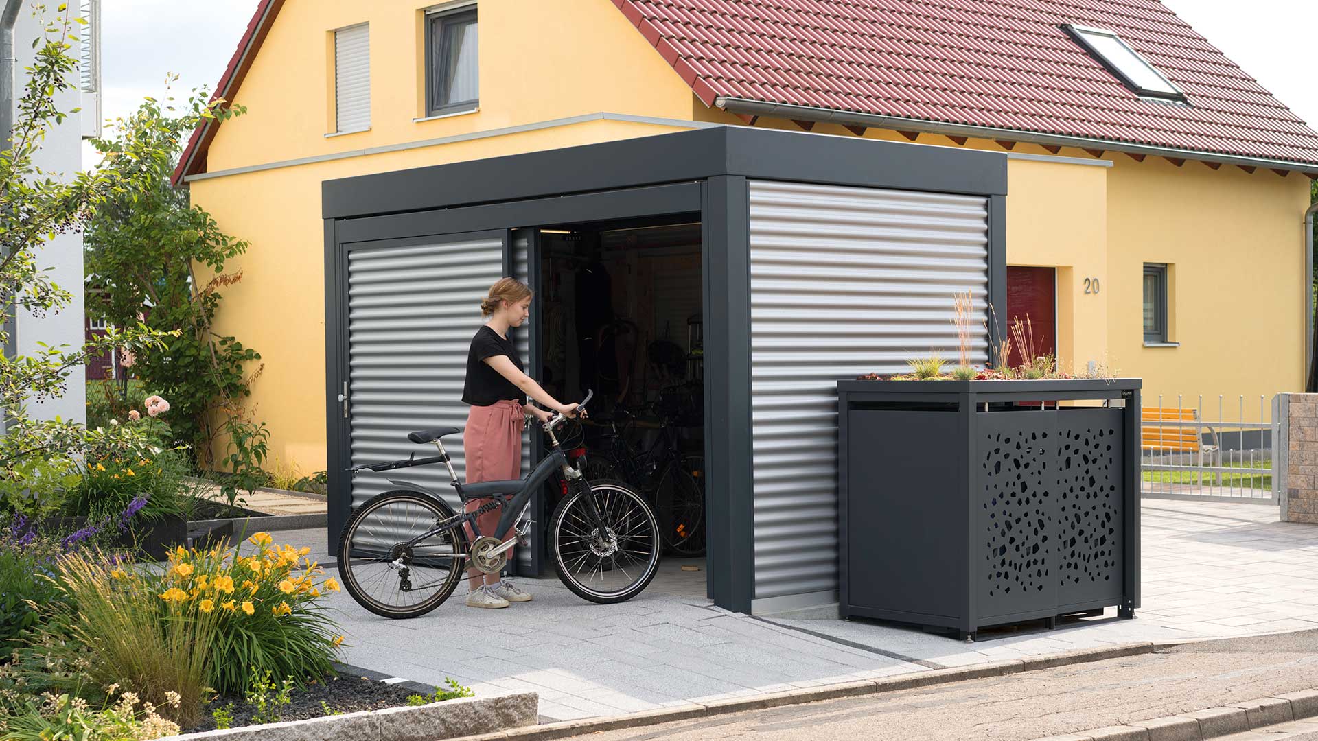 Fahrradhaus MULTIPORT® und Müllbehälterschrank STYLEOUT TOMO vor einem Haus