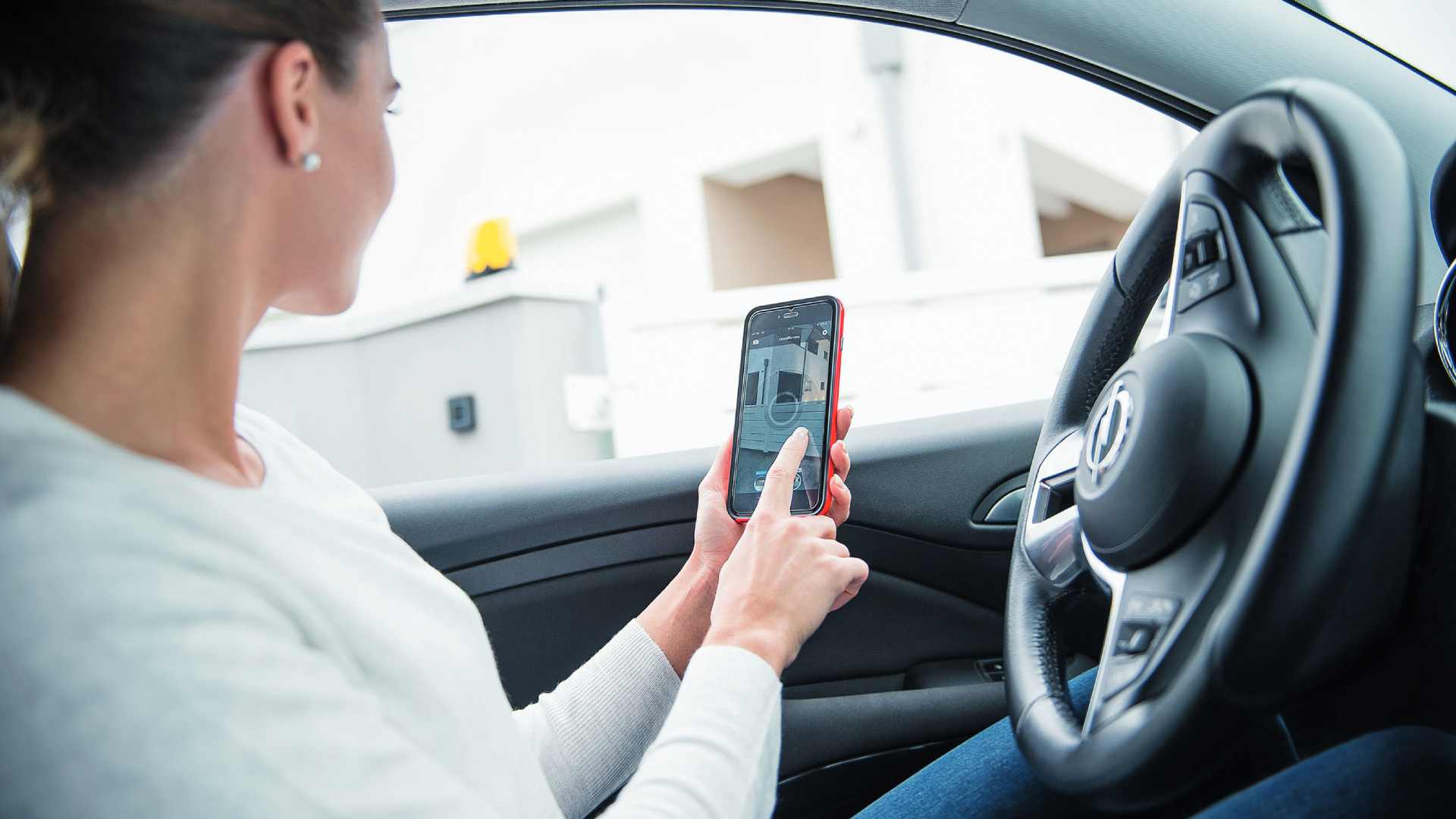 Frau nutzt ihr Smartphone um ein Bedienelement im Bereich Poller zu steuern
