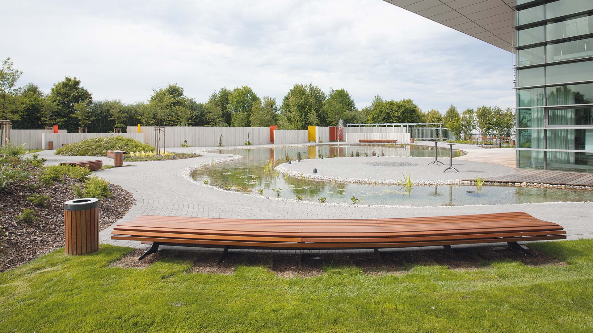 Geschwungene lange Sitzbank aus Holz an einem Teich