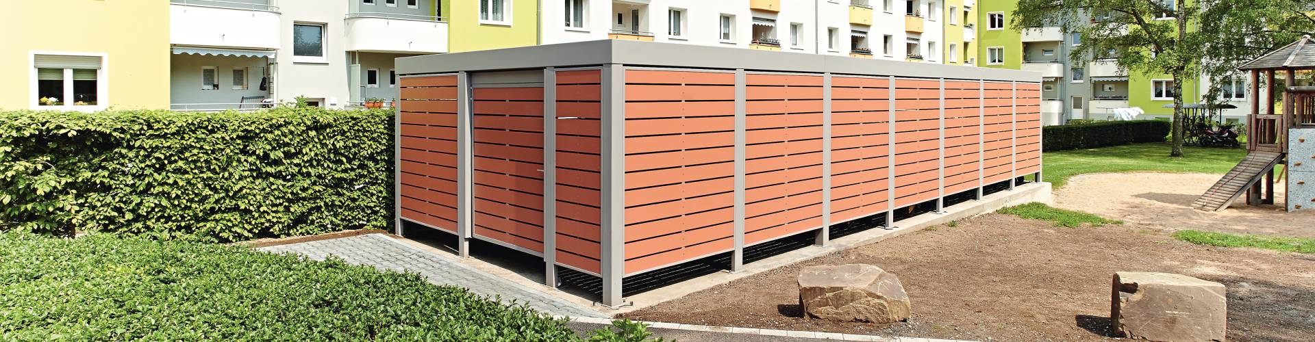 Mülltonnenbox Multiport mit Holzoptik in einer Wohnsiedlung