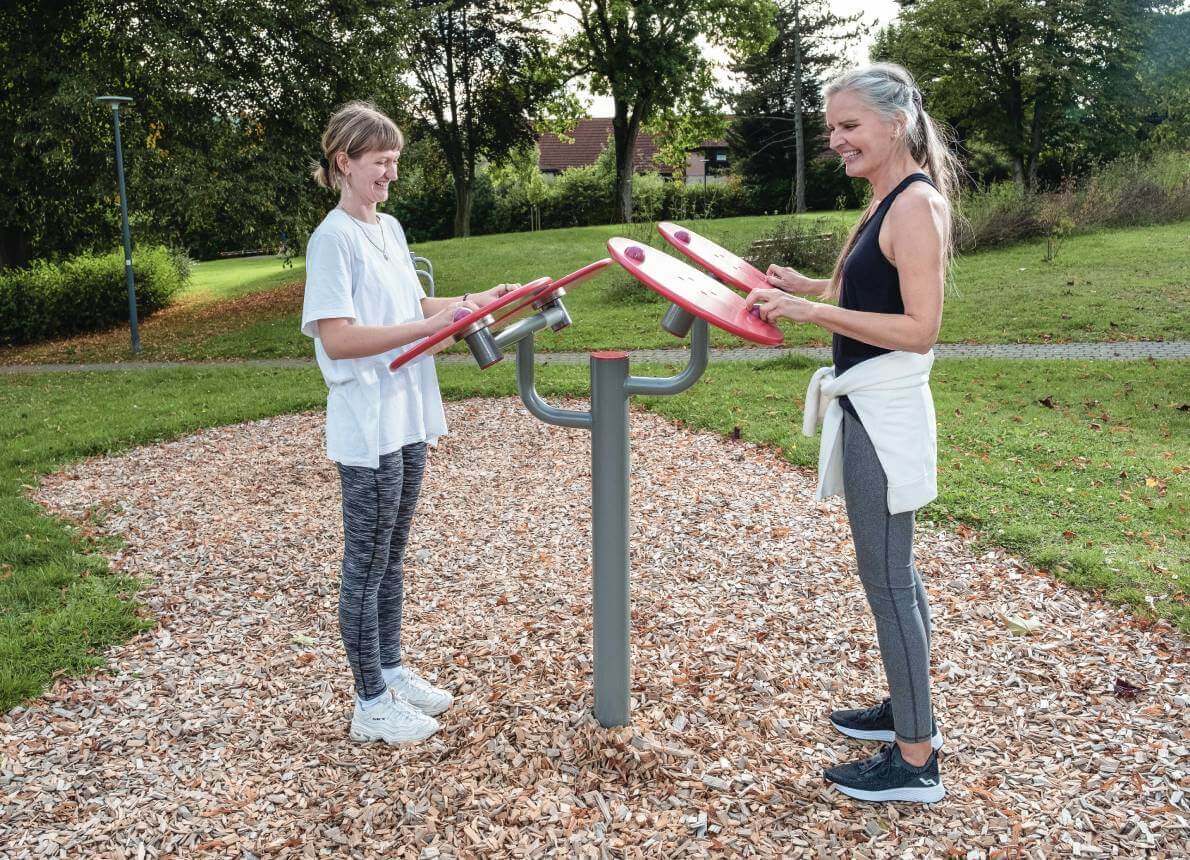 Zwei Frauen stehen an einer Outdoor Sportplatz Anlage in einem Park