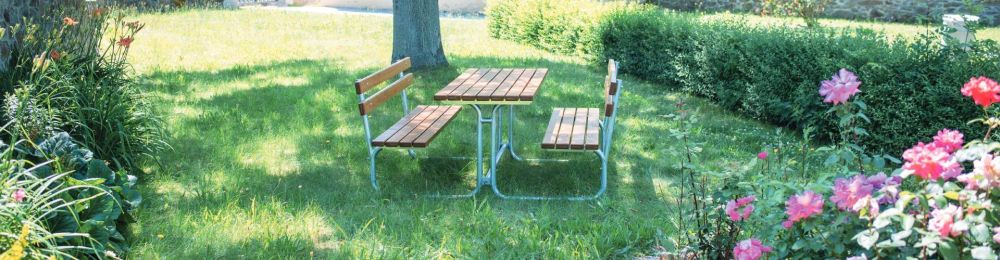 Eine Bank Tisch Kombination steht in einem grünen Park auf einer Wiese
