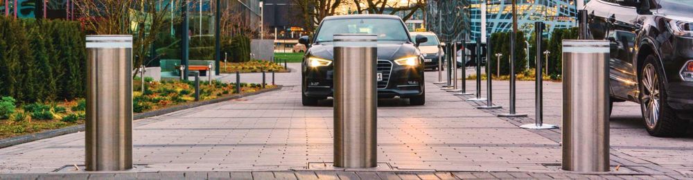 Drei versenkbare Poller CUPRIT mit einem Auto im Hintergrund