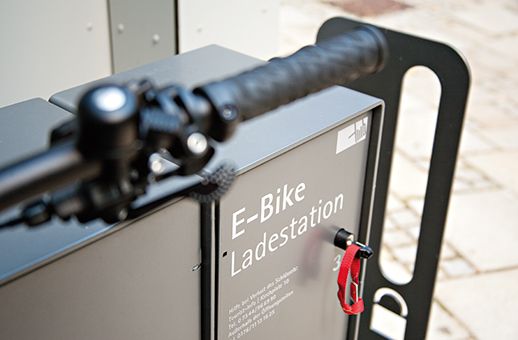 E-Bike-Ladestation mit rotem Schlüsselanhänger an einem schwarzen Fahrradlenker