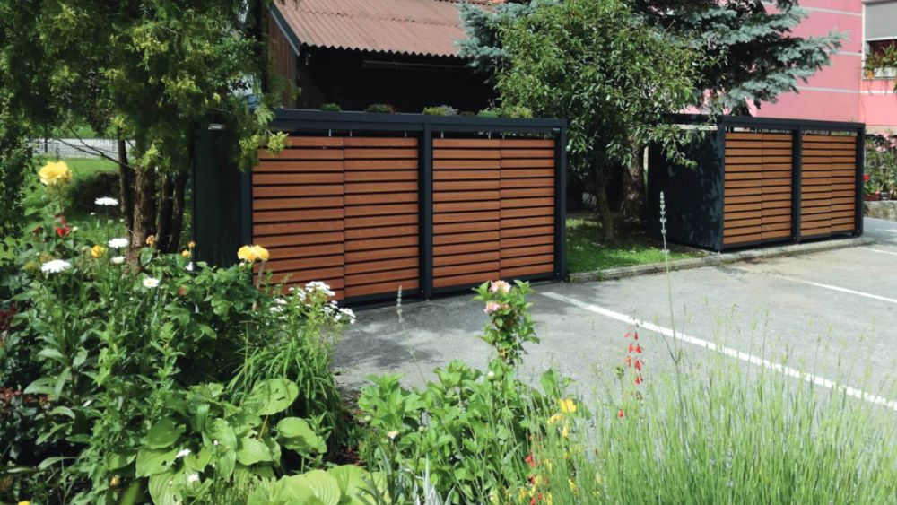 zwei Mülltonnenboxen in grüner Umgebung