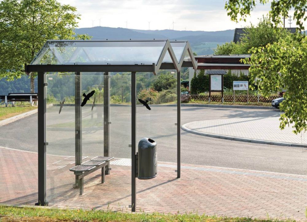 Wartehalle mit Vogelschutz Aufklebern vor einer hügeligen Landschaft