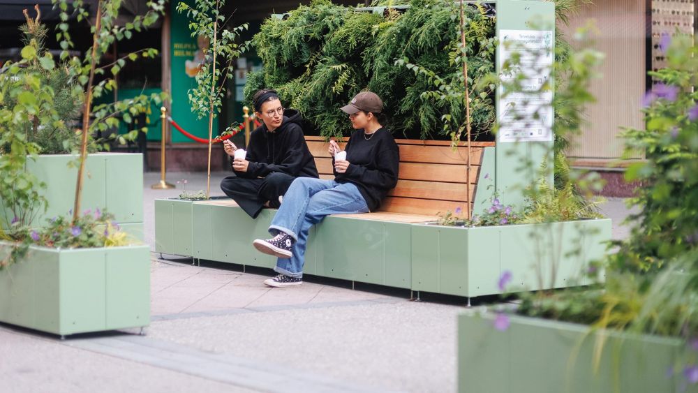 Begrünter Sitzinsel auf der zwei Frauen sitzen