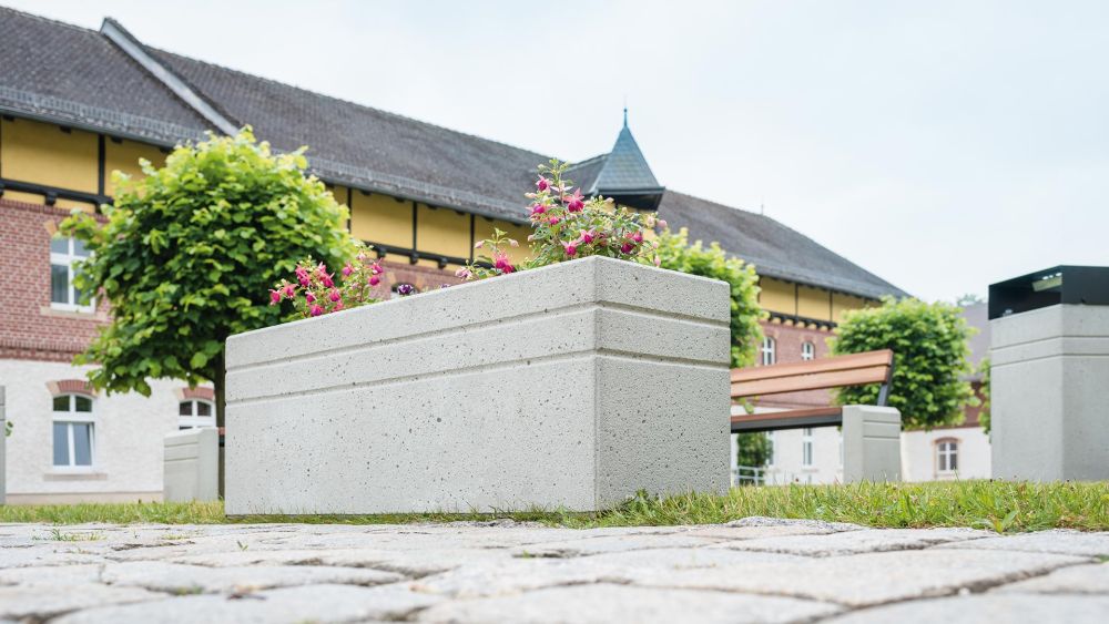 Moderne Pflanzbehälter aus Beton steht auf dem Vorhof eines Gehöfts