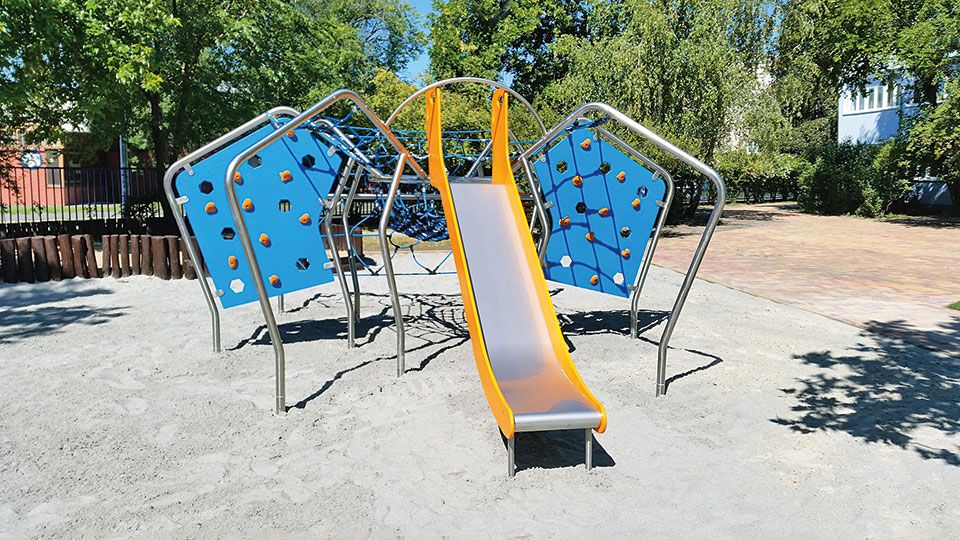 Klettergerüst, blauen Kletterwänden und gelber Rutsche auf Sandfläche