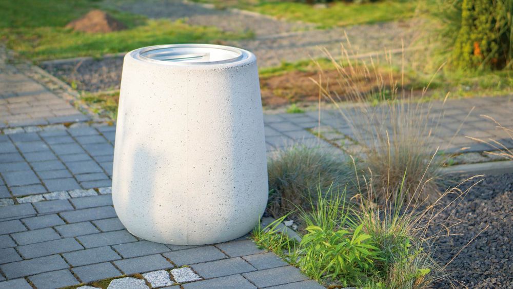 Moderner, weißer Müllbehälter aus Beton auf einem gepflasterten Weg