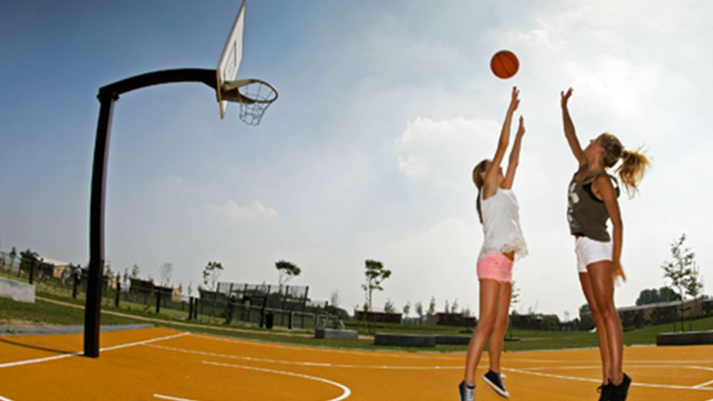 Basketballplatz mit Basketballkorb Sitzbank mit Holzbelattung von VelopA auf dem zwei Frauen spielen