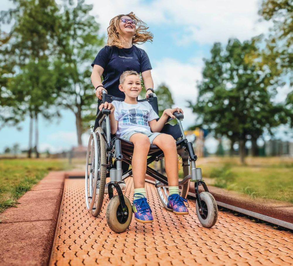 Kind im Rollstuhl auf einem barrierefreien Bodentrampolin